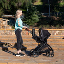 Load image into gallery viewer, A mom is pushing her baby in the Baby Trend Passport Switch 6-in-1 Modular Stroller