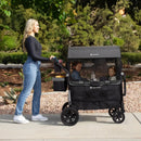 Load image into gallery viewer, A mom is pushing her two children sitting in the Baby Trend Quest 3-in-1 Stroller Wagon