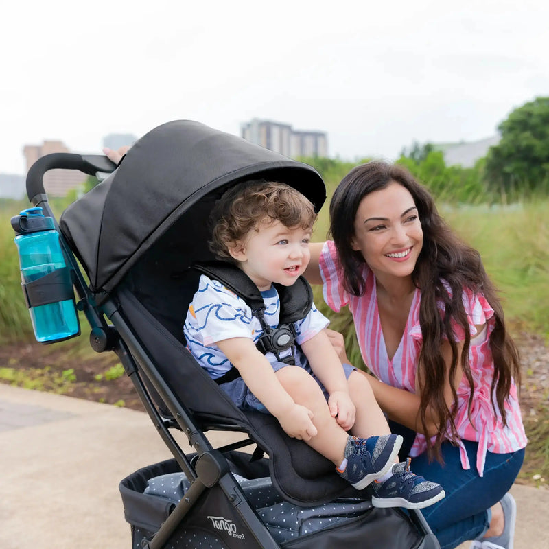 A mom is outdoor with her child sitting in the Baby Trend Tango Mini Stroller