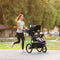 Mom is jogging while pushing her child in the Baby Trend Expedition DLX Jogger