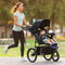 A mom is jogging with her child riding in the Baby Trend Expedition DLX Jogging Stroller