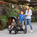 Load image into gallery viewer, Mom and her two kids strolling outdoor with the Baby Trend Morph Single to Double Modular Stroller Travel System