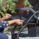 Load image into gallery viewer, A mom is converting the stroller into a carriage mode with the Baby Trend Passport Carriage DLX Stroller Travel System