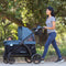 Mom is pushing her two children in the Baby Trend Navigator 2-in-1 Stroller Wagon