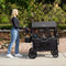 A mom is pushing her two children sitting in the Baby Trend Quest 3-in-1 Stroller Wagon
