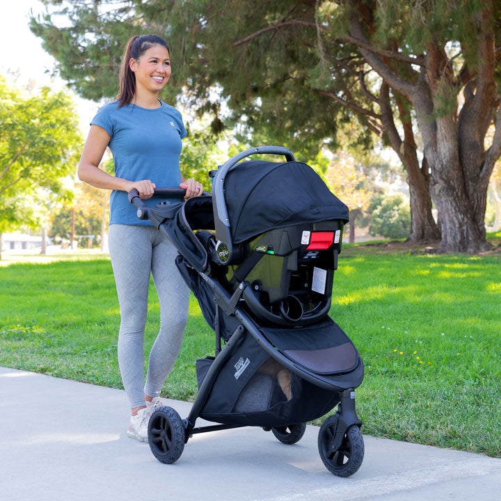 MUV by Baby Trend Tango Pro Travel System in Uptown Brown fashion with Ally 35 Infant Car Seat, mother strolling with her baby 