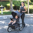 Load image into gallery viewer, Mom is pushing her child in the Baby Trend Expedition Jogger Stroller outside 