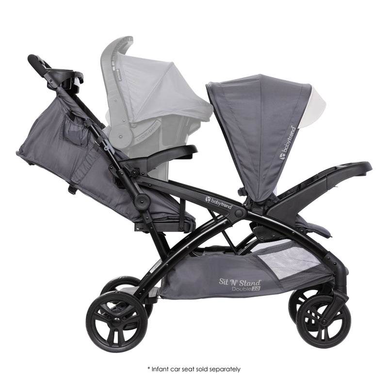 Side view of the Baby Trend Sit N' Stand Double 2.0 Stroller with an infant car seat in the rear seat for a travel system