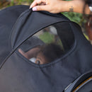 Load image into gallery viewer, A parent is checking on their child from behind the stroller using the peek-a-boo window on the canopy of the Baby Trend Passport Seasons All-Terrain Stroller Travel System