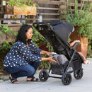 Load image into gallery viewer, Adventuring in the outdoor with her child, the mom access the extra large storage basket from the Baby Trend Passport Seasons All-Terrain Stroller Travel System