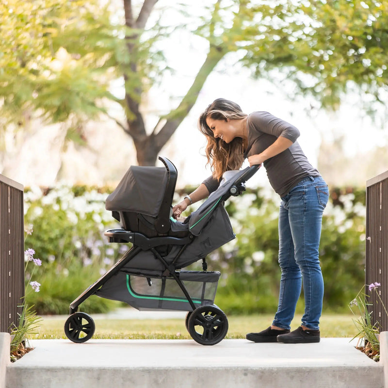 Mom is checking on her baby in the car seat on the stroller of the Baby Trend EZ Ride Stroller Travel System with EZ-Lift 35 Infant Car Seat